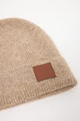 Gorro tejido de punto con doblez en el borde y aplique de cuero sintético con logo grabado en el frente.