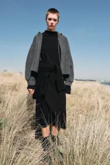 Chaqueta de punto con capucha, manga larga y cierre frontal con cremallera metálica. Presenta un diseño de tejido texturizado en color gris oscuro con detalles en contraste en los puños.