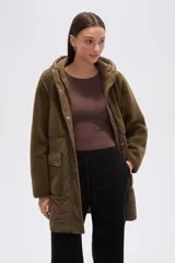 Campera de diseño híbrido en color verde oliva, que combina paneles de corderito en la parte superior y capucha con una sección inferior acolchada con diseño de rombos. Cuenta con cierre frontal, botones a presión y bolsillos frontales con solapa.