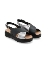 Sandalia de plataforma con tiras cruzadas en cuero negro y plateado, con ajuste de hebilla metálica lateral y suela de poliuretano.