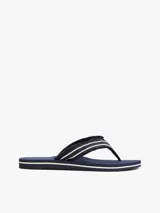 Ojotas Tommy Hilfiger azul marino con tiras de tela trenzada con rayas blancas y suela plana.