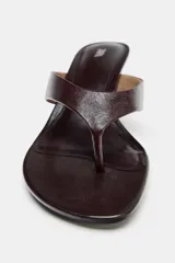 Sandalia tipo mule de piel color marrón oscuro, con diseño de tira entre los dedos y tacón fino de altura media.