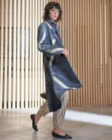 Tapado gris de lana merino afieltrada, con cuello que se prolonga a modo de cinto, aberturas y bolsillos laterales. Diseño artesanal teñido con técnica Tie Dye.