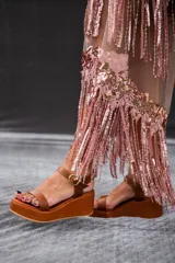 Sandalias de plataforma con taco cuña color marrón y tiras doradas metalizadas en el empeine y el talón. Cuentan con tira ajustable con hebilla metálica en el tobillo.