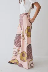 Pantalon de corte wide leg y tiro alto, confeccionado en tela con estampado deportivo que incluye pelotas de futbol y raquetas de tenis en tonos verde, rosa y beige.