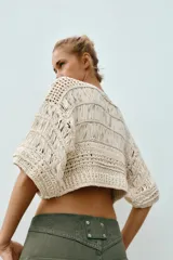 Top cropped de punto con diseño combinado de texturas, cuello redondo y mangas cortas amplias. Presenta una estructura calada con detalles de cintas verticales.