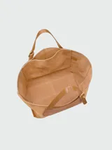 Bolso tote XL Longchamp modelo Complice Softy, confeccionado en gamuza marrón claro con detalle frontal ovalado y asas de cuero liso en tono tostado.