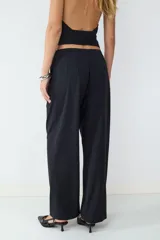 Pantalón negro de tiro medio, confeccionado en tejido fluido, de pernera recta con pinzas delanteras y cierre frontal oculto.