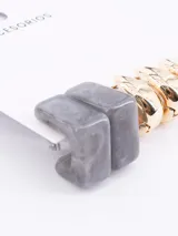 Set de tres pares de aros: un par de aros tipo botón con forma cuadrada y diseño marmolado en tonos grises, un par de aros tipo argolla gruesa y un par de aros tipo argolla fina, ambos en color dorado.