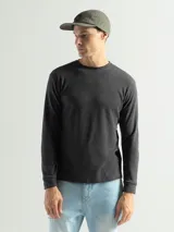 Remera de manga larga con cuello redondo, confeccionada en tejido de algodón tipo mini piqué. Presenta un diseño versátil con puños elásticos en las mangas, ideal para usar como prenda base o como buzo ligero.