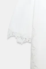 Camiseta blanca de manga corta y cuello redondo, confeccionada en hilatura de algodón con detalle de aplicación de encaje a tono en las mangas y los laterales.
