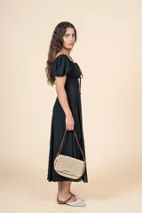 Vestido midi de color negro, con escote cuadrado, mangas cortas abullonadas y detalle de frunces con lazo en el centro del pecho. Presenta una silueta entallada en la cintura y falda con caída fluida.