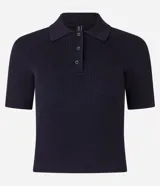 Polo de manga corta color azul marino, confeccionado en punto acanalado, con cuello polo y tapeta de tres botones. Presenta un bolsillo de parche en el lado izquierdo del pecho.