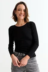 Sweater de tejido de punto fino en color negro, con cuello redondo y mangas largas, de corte ajustado al cuerpo.