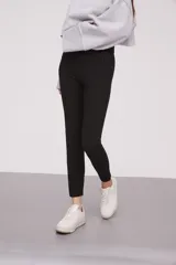 Calza negra de tiro alto con cierre lateral y detalle de costura en la rodilla.