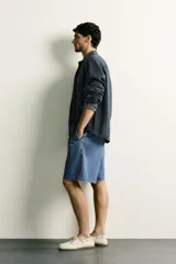 Camisa relaxed fit de lino color negro con efecto lavado, cuello clásico, manga larga con puños abotonados y dos bolsillos de parche con solapa en el pecho.