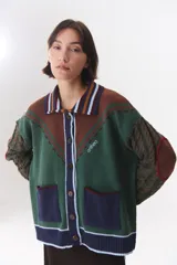 Cardigan de punto con diseño multicolor en tonos marrones, bordó y detalles en amarillo y celeste. Presenta cuello tipo polo, cierre frontal con botones, bolsillos aplicados en el frente y mangas con trama trenzada y coderas bordadas.