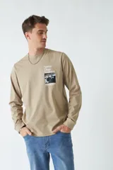 Remera de hombre color beige con cuello redondo y estampado frontal con texto "Sunday Village Vanguard" y una fotografía en blanco y negro de un pianista tocando en un club de jazz.