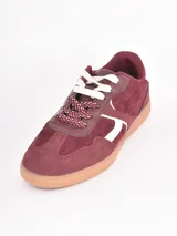 Championes de estilo urbano en color bordó, confeccionados en gamuza con detalles en cuero blanco. Presentan cordones gruesos con estampado de lunares y suela de goma color caramelo.
