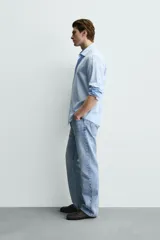 Camisa de corte regular fit confeccionada en tejido de algodón con textura twill. Presenta cuello italiano, manga larga con puños abotonados y cierre frontal de botones.