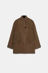 Blazer oversize de Zara Woman Collection confeccionado en mezcla de lana, con cuello sin solapa, manga larga y cierre frontal con botón. Presenta bolsillos delanteros con solapa.