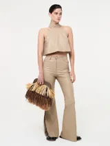 Top corto color beige, estilo halter con cuello alto y espalda descubierta. Confeccionado en eco cuero.