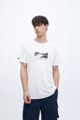 Remera blanca de algodón con cuello redondo y manga corta. Estampado fotográfico en el pecho con texto.