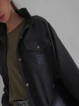 Camisa de lana color gris oscuro, de corte clásico con bolsillos frontales con solapa, cuello camisero y cierre frontal con botones.