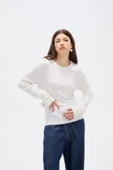 Remera de manga larga confeccionada en viscosa, con ajuste al cuerpo, cuello redondo y detalle de botones metálicos en los puños.