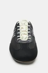 Zapatilla deportiva estilo running color negro, con combinación de materiales, pespuntes decorativos blancos, talón en contraste y cordones claros.