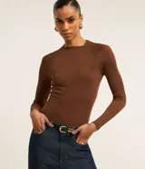 Blusa de manga larga con diseño ajustado, confeccionada en tejido acanalado de viscosa con elastano. Presenta cuello redondo y sisas raglán.
