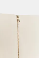 Pantalón de vestir color crudo, de tiro alto y pierna acampanada.