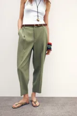 Pantalón verde oliva de lino con tiro alto, pinzas delanteras, bolsillos frontales y falsos bolsillos con solapa en la espalda. Incluye cinturón marrón y cierre delantero con cremallera, botón interior y gancho.