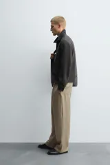 Pantalón negro de corte relajado con cintura elástica ajustable y pliegues en la parte delantera. Presenta bolsillos laterales y bolsillos traseros de parche.