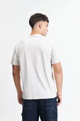 Remera de manga corta color beige claro, con escote redondo y fit regular. Presenta un estampado frontal con letras góticas en blanco.