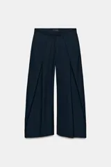 Pantalón de tiro medio de corte wide leg, confeccionado en mezcla de lyocell con patrón de rayas diplomáticas. Presenta bolsillos laterales ocultos, pliegues delanteros marcados y cierre frontal con cremallera, botón y ganchos metálicos.