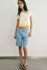 Top de punto color crudo con cuello redondo, manga corta y detalles de rib en color amarillo en el cuello, los puños y el ruedo.