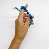 Collar elaborado con bolitas de ágata azul de 10 mm de diámetro, con separadores de hilo color turquesa. El cierre es un broche tipo T (toggle) de metal con baño de oro.