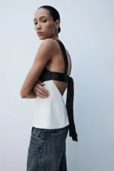 Top de escote cuadrado y tirantes anchos, con diseño bicolor en negro en la parte superior y blanco en el cuerpo, corte ligeramente acampanado y espalda descubierta con lazada.