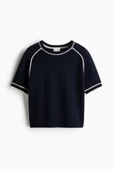 Remera corta de punto suave azul marino, con cuello redondo acanalado, mangas cortas y ribetes blancos en contraste en el cuello, costuras de las mangas y puños.