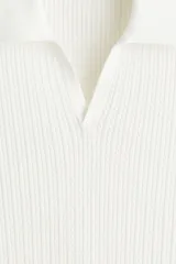 Remera polo de manga corta en punto trenzado suave, color blanco, con cuello abierto y remate acanalado en mangas y bajo.