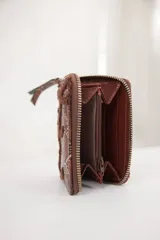 Billetera pequeña con cierre perimetral, confeccionada en material con estampado de piel de serpiente y detalle de bordado en relieve de color negro.