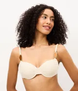 Top de bikini confeccionado en microfibra acanalada, de color beige con aros estructurados y breteles regulables con apliques decorativos ovalados.