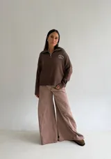 Sweater de punto color marrón, con cuello polo y cierre frontal, manga larga y diseño holgado con puños y ruedo acanalados. Presenta un pequeño bordado en el pecho.