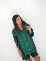 Camisa negra de satén con brillo satinado, escote en V, mangas largas y botones de nácar. Cuenta con cordones laterales ajustables para fruncir la prenda.
