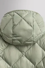 Campera puffer verde oliva acolchada con diseño de rombos, capucha y cierre frontal con cremallera. Incluye bolsillos laterales con cierre. Relleno de plumón y plumas.
