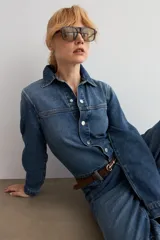 Mono de jean de corte recto y manga larga, con cierre frontal de botones metálicos, cuello camisero y costuras reforzadas. Incluye presillas para cinturón.