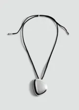 Collar con dije metálico de forma orgánica y superficie lisa brillante, montado sobre un cordón negro ajustable.