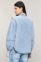 Camisa de denim celeste con calce regular, cuello camisero, cierre frontal con botones metálicos y mangas estilo balloon con puños largos ajustables.