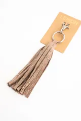 Charm para bolso compuesto por flecos de cuero sintético color marrón, decorados con pequeñas tachas metálicas doradas. Incluye un aro y un cierre de mosquetón metálico en tono dorado.